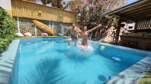 a man and a woman are jumping in a swimming pool at Puerto Bamboo in Máncora