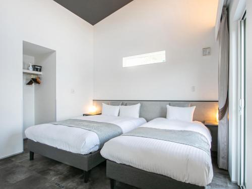 Dos camas en una habitación con paredes blancas. en Kubikai, en Itoshima