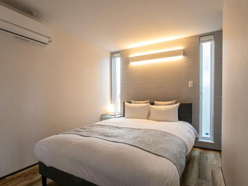 Un dormitorio con una gran cama blanca con ventana. en Kubikai, en Itoshima