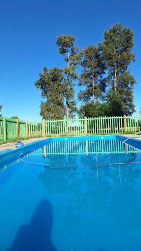 Una piscina azul con valla y árboles. en Paraíso Rustico 3, en Curacautín