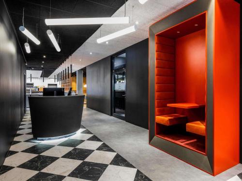 Una oficina con un vestíbulo naranja y negro con un mostrador. en ibis Duesseldorf Airport, en Düsseldorf