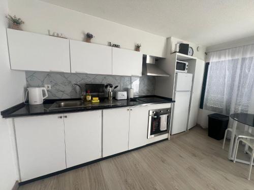 a white kitchen with a sink and a refrigerator at Serenity Apartment in Funchal
