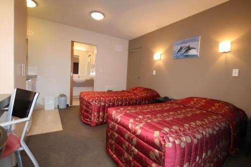 a hotel room with two beds and a desk at Bella Vista Motel Kaikoura in Kaikoura
