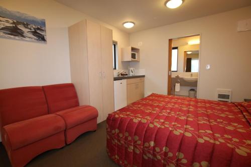 a bedroom with a bed and a couch and a kitchen at Bella Vista Motel Kaikoura in Kaikoura