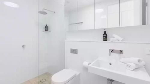 a white bathroom with a toilet and a sink at The Avenue in Sawtell