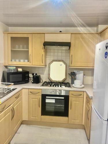a kitchen with wooden cabinets and a stove top oven at 4 Bed Detached Home Perfect for Families & Groups in Glasgow