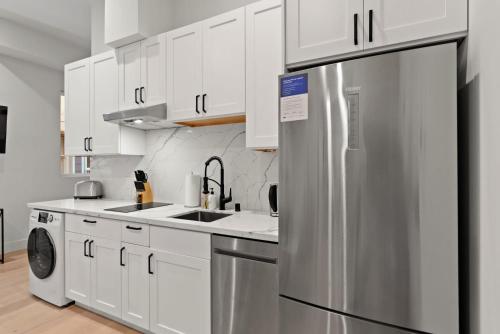 a kitchen with white cabinets and a stainless steel refrigerator at Kasa The Addison San Francisco in San Francisco