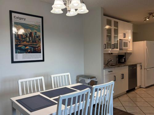 a kitchen with a table and chairs and a kitchen with a refrigerator at Chic & Spacious 2BR at Stampede with Parking, AC in Calgary