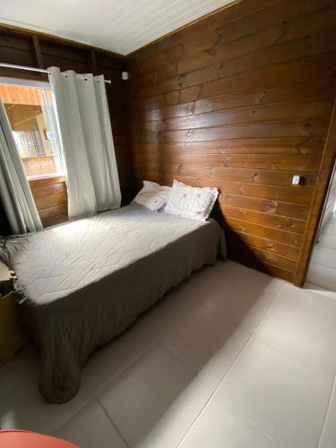 Un dormitorio con una cama con una pared de madera. en Casa com Piscina em Itapirubá, en Imbituba