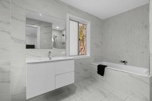 Nine Acres Bush & Bay Haven with Pool access في Murrays Beach: حمام أبيض مع حوض وحوض استحمام