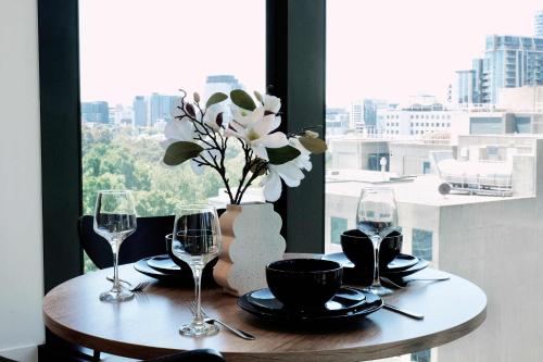 una mesa con copas de vino y un jarrón con flores en 1Br City View apt near SthnCrs Wifi Pool Gym, en Melbourne