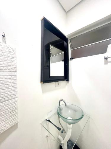 a glass table in a bathroom with a mirror at Mar Doce Lar Kitinete in São Vicente