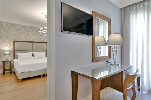 a room with a desk with a television and a bed at Anaktorikon Boutique Hotel in Tripolis
