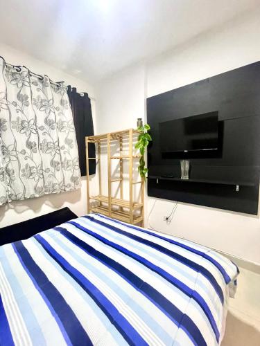 a bedroom with a bed and a flat screen tv at Mar Doce Lar Kitinete in São Vicente
