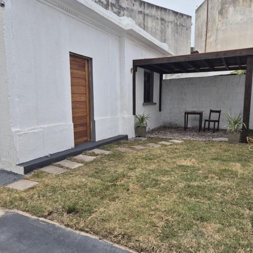 un edificio blanco con puerta de madera y patio en Casa en el centro de Piriapolis a 1 cuadra de la playa, en Piriápolis