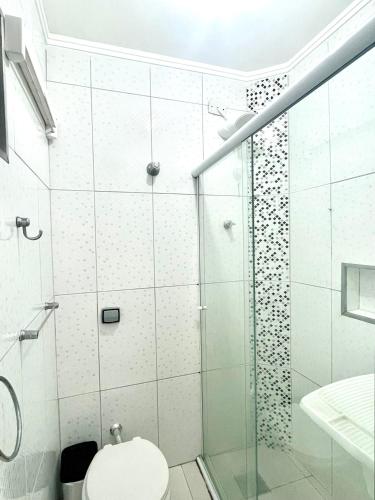 a white bathroom with a shower and a toilet at Brisa do mar Kitinete in São Vicente