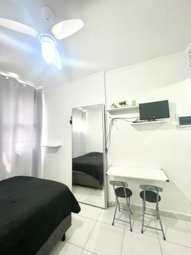 a bedroom with a bed and a desk with two chairs at Brisa do mar Kitinete in São Vicente