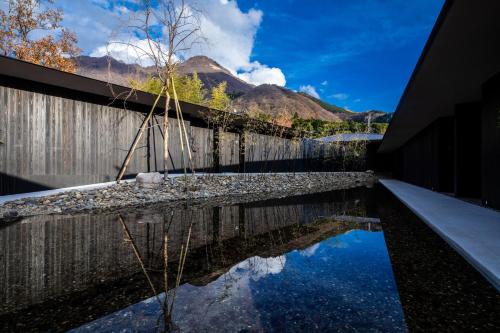 a pool of water with a fence and mountains in the background at Hotel MODA in Yufu