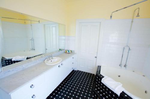 Carrington Hotel في كاتومبا: حمام مع حوض استحمام ومغسلة ومرآة