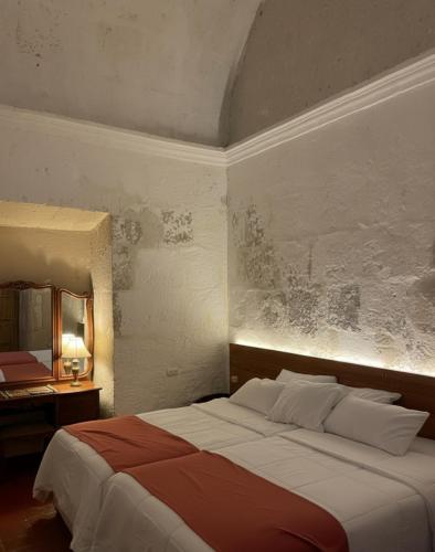 a bedroom with a large bed and a mirror at Hotel Piru Wasi in Arequipa