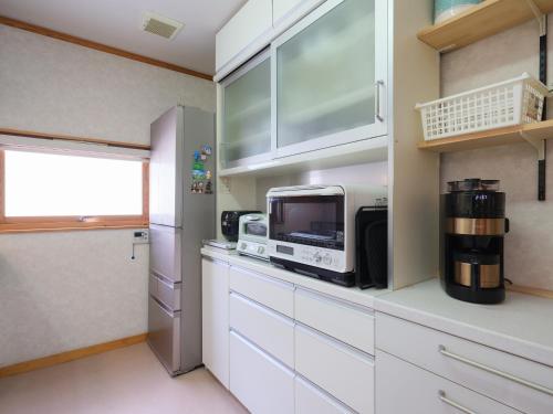 a kitchen with white cabinets and a microwave at Urayasu Horie House in Tokyo