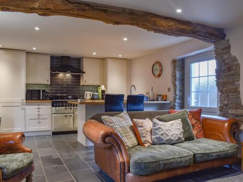 Honeysuckle Cottage في High Bickington: غرفة معيشة مع أريكة ومطبخ