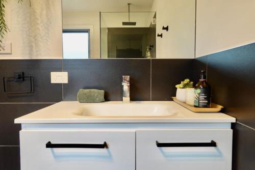 a bathroom with a white sink and a mirror at Paradise - Spacious, Ocean Views, Outdoor Living in Dodges Ferry