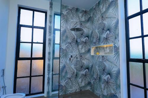 a bathroom with a shower with a mural of leaves at Kokasemera Country Villa in Fort Portal