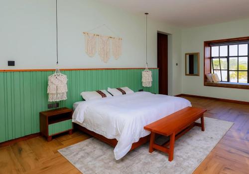 a bedroom with a white bed and a wooden floor at Kokasemera Country Villa in Fort Portal