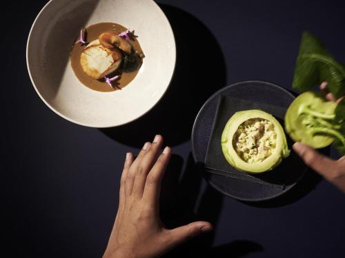 una persona que alcanza un plato de comida en una mesa en Raffles Udaipur, en Udaipur