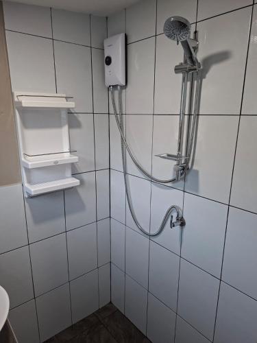 a shower in a white tiled bathroom with a shower head at Bee Nat Garden Resort in Bangrak Beach