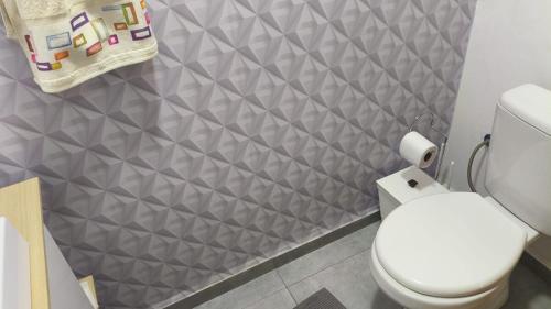 a bathroom with a white toilet and a gray wall at Casa espaçosa no coração de Floripa in Florianópolis
