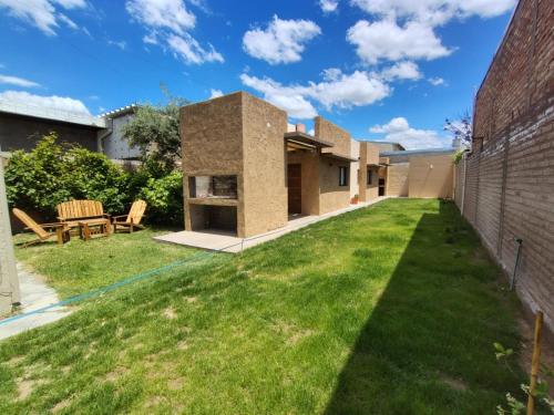 ein Hinterhof mit grünem Gras und einem Backsteingebäude in der Unterkunft Complejo Entre Parras in San Rafael