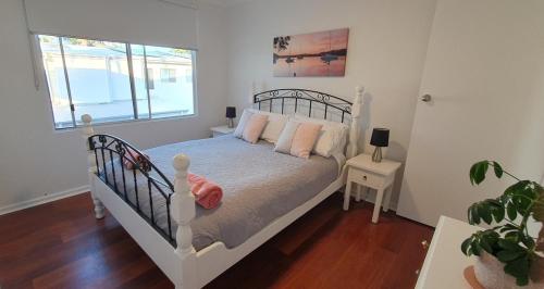 ein Schlafzimmer mit einem weißen Bett mit rosa Kissen in der Unterkunft Sensational Waterfront Apartment in Dunbogan