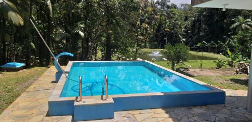 een blauw zwembad met een glijbaan in een tuin bij PARAISO do TOMATE in Antonina