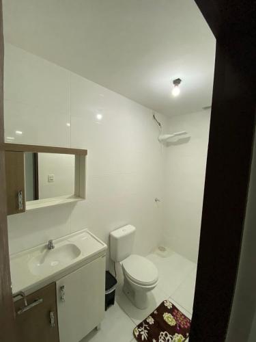a white bathroom with a toilet and a sink at Pé na Guarita in Torres