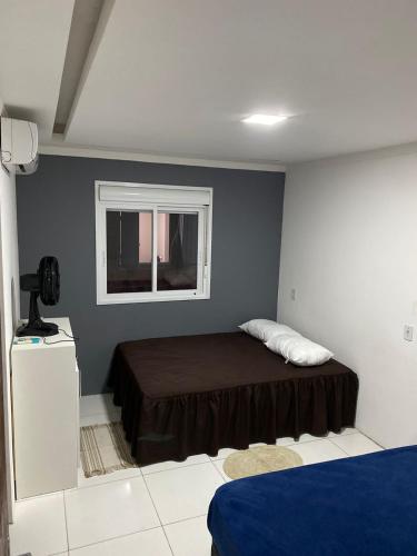 a small bedroom with a bed and a window at Pé na Guarita in Torres