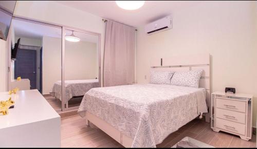 a white bedroom with a bed and a mirror at Caribbean Breeze in Punta Cana