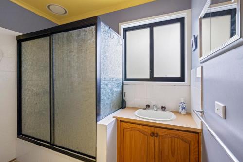a bathroom with a sink and a glass shower at Treehouse at Cape in Cape Paterson