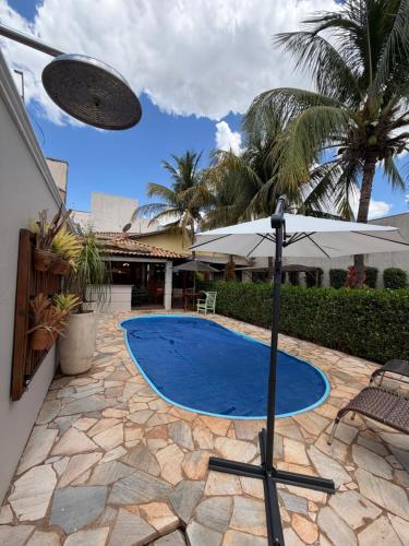 een zwembad in een achtertuin met een parasol bij Casa Magnífica in Olímpia