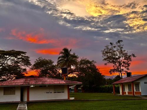 a sunset over a house with a palm tree at Hotel Campestre Cinco Estrellas in Villavicencio