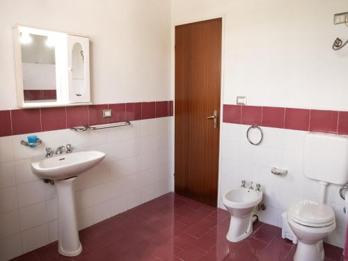 a bathroom with a sink and a toilet and a mirror at Spacious villa with a large veranda and pool in Floridia