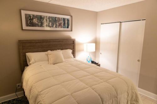 a bedroom with a large bed and a lamp at Serenity Escapes Waterfront Atlantic City Condo with Balcony & Free Parking in Atlantic City
