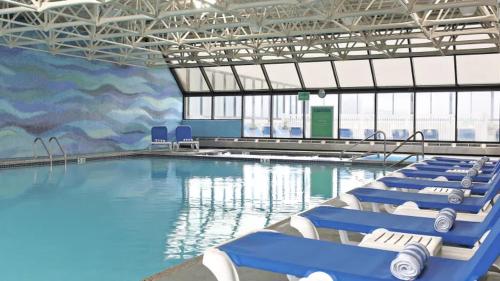 a large swimming pool with blue chairs in a building at Serenity Escapes Waterfront Atlantic City Condo with Balcony & Free Parking in Atlantic City