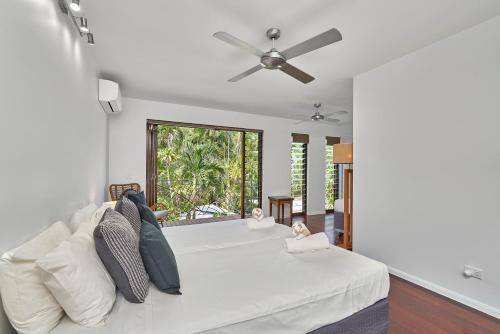 een slaapkamer met een wit bed met een plafondventilator bij Onda Beach Clifton Beach in Clifton Beach