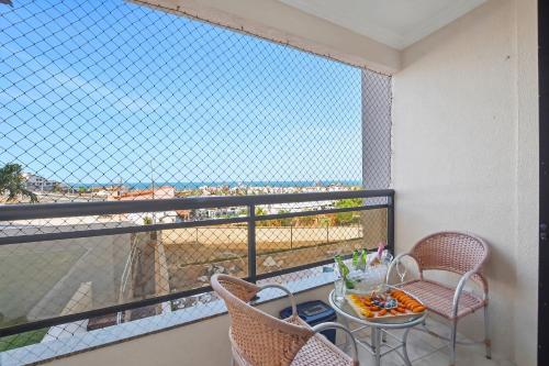 Studio no Porto das Dunas vista mar e Beach Park! في Mangabeira: شرفة مع كرسيين وطاولة مع وعاء من الطعام