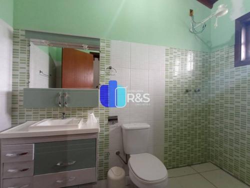 een badkamer met een toilet, een wastafel en een spiegel bij Chácara com 3 dormitórios in Louveira