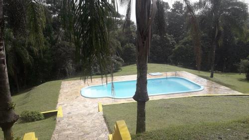 een zwembad in een tuin met een palmboom bij Chácara com 3 dormitórios in Louveira