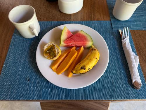 a white plate with fruit and vegetables on a table at Lily Mirissa in Mirissa
