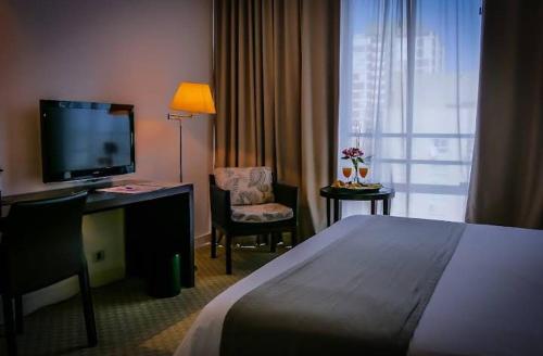 Mar de Ajó hostal في مار دي آخو: غرفة فندقية تحتوي على سرير ومكتب وتلفزيون